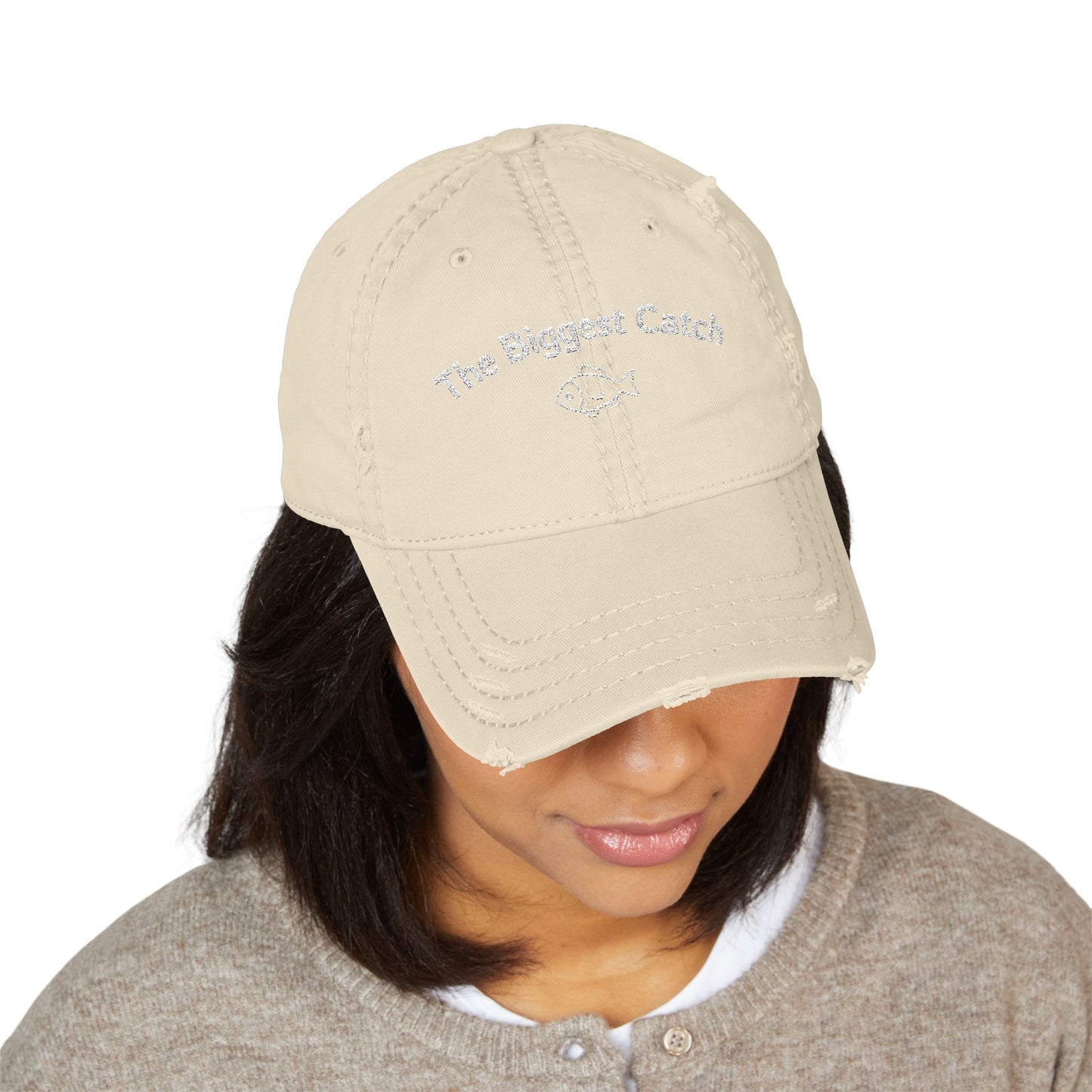 Beige cap with 'The Biggest Catch' text worn by a person on a white background