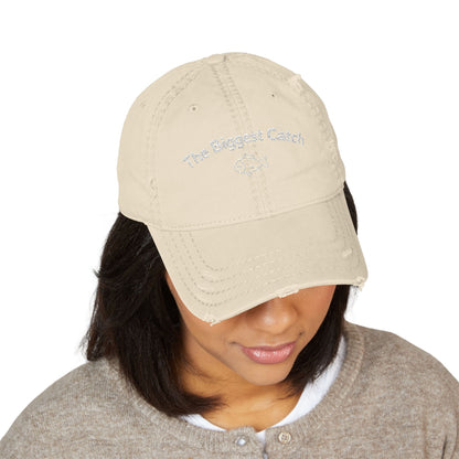Beige cap with 'The Biggest Catch' text worn by a person on a white background